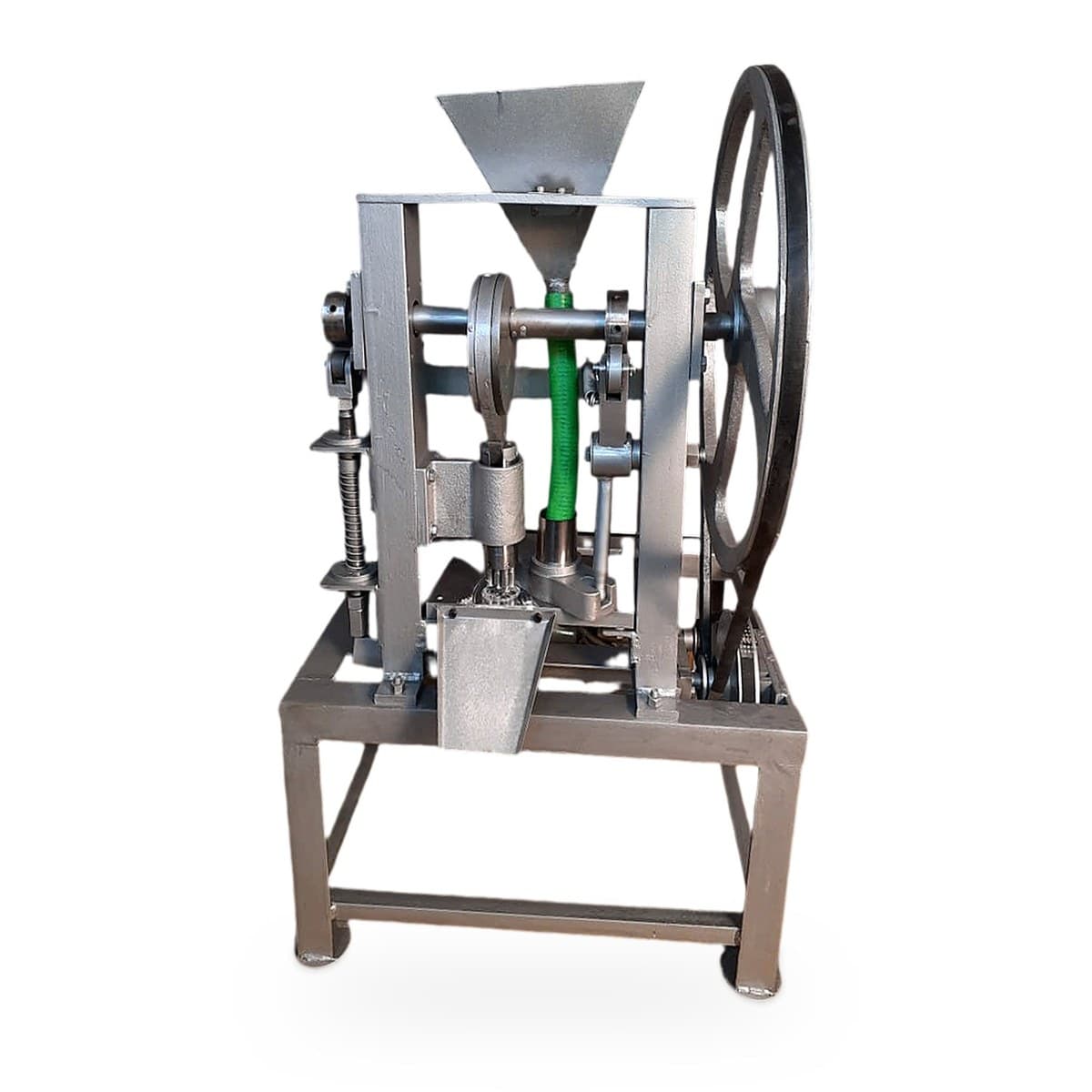 Semi automatic camphor tablet making machine with a hopper on top, green feed pipe, punch assembly, outlet chute and a large flywheel on an MS stand