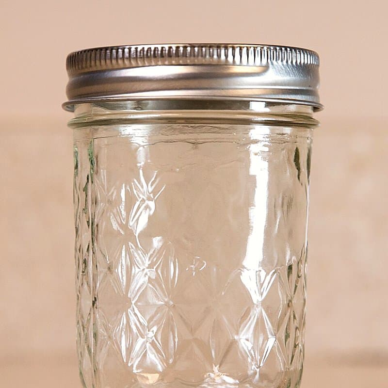 Empty clear glass jar with a metal screw lid