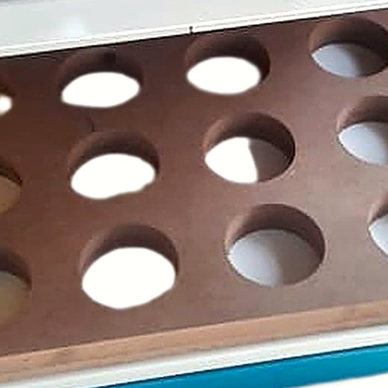 Wooden tray with round pockets that hold blisters under a sealing plate