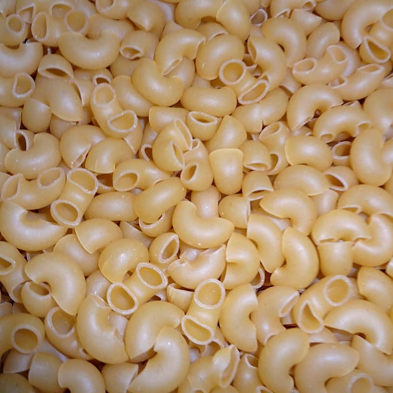 Dry elbow macaroni pieces filling the frame