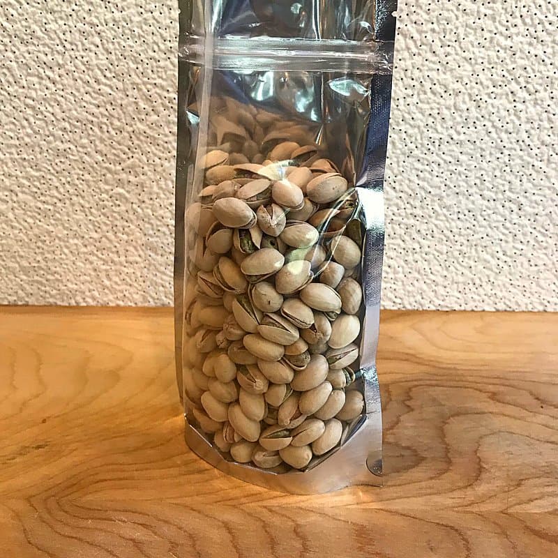 Metallised stand-up pouch filled with pistachios on a wooden table