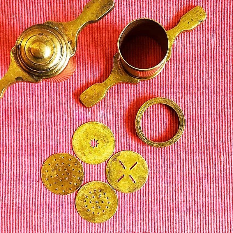 Brass hand-held chakli press with its set of interchangeable die discs, showing how die patterns shape the dough