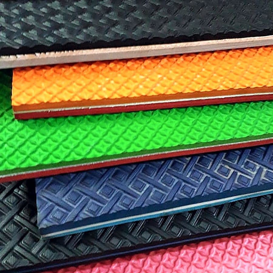Stacked EVA soling sheets in black, orange, green, blue and pink with embossed tread patterns