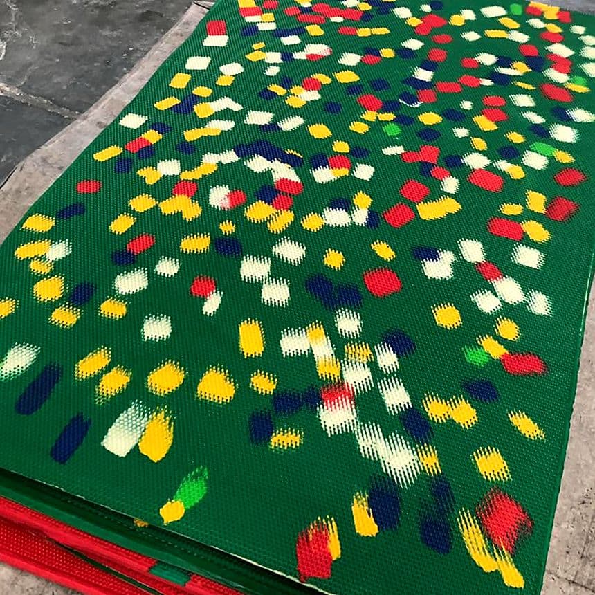 Green printed EVA slipper sheets with a multicoloured splash pattern, stacked on a workshop floor